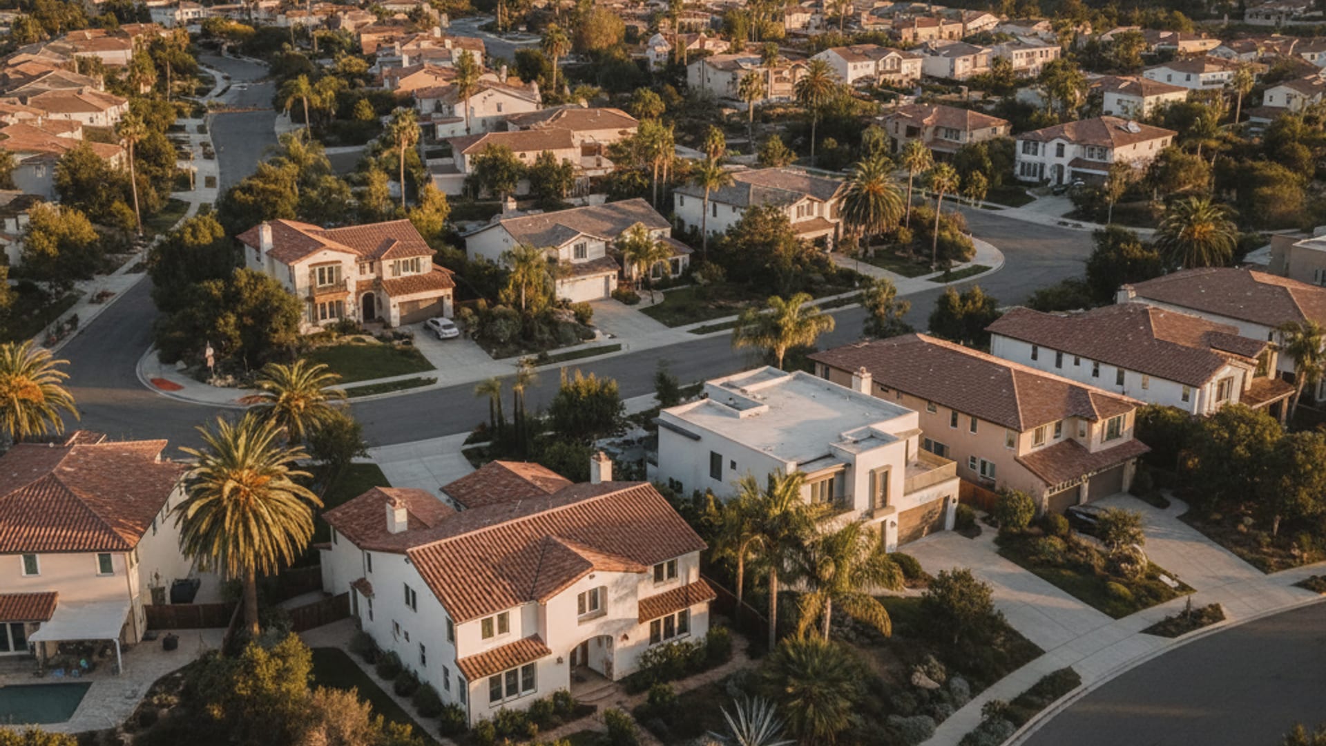 Aerial view of a San Diego County residential neighborhood with stucco homes and terracotta roofs at golden hour